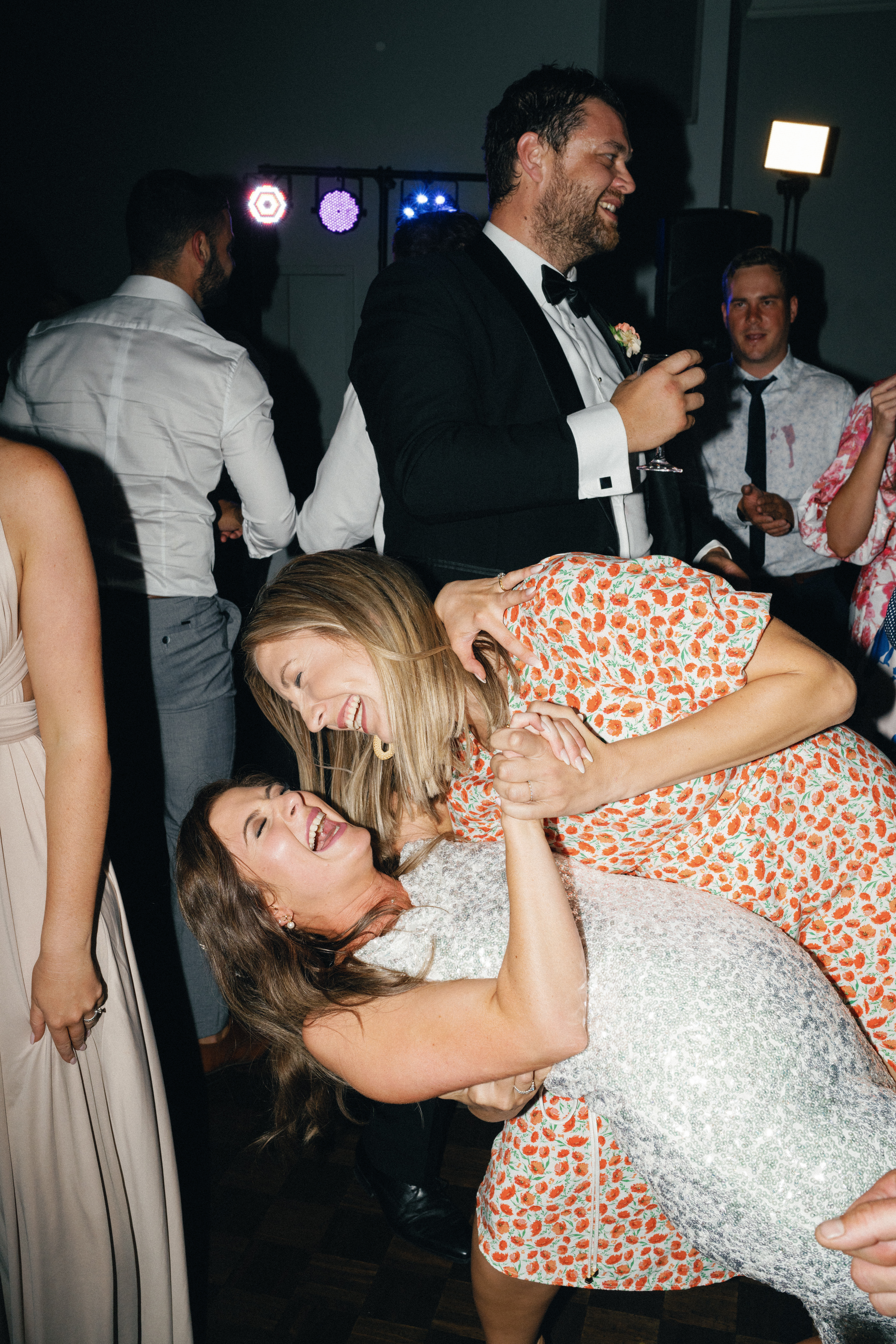 An image shot using flash photography of a bride partying on the dance floor with her friend.