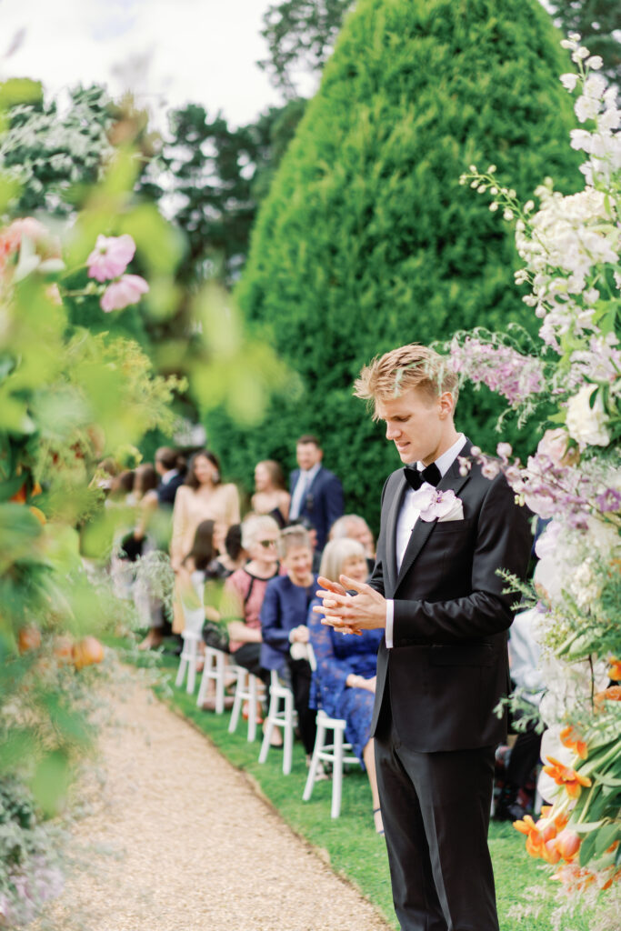 The groom waits for his bride at his garden wedding ceremony